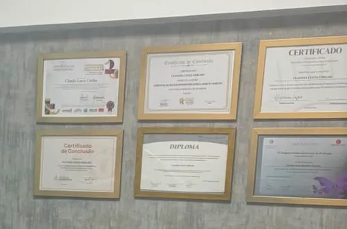 Seis certificados e diplomas emoldurados na parede da sala de atendimento